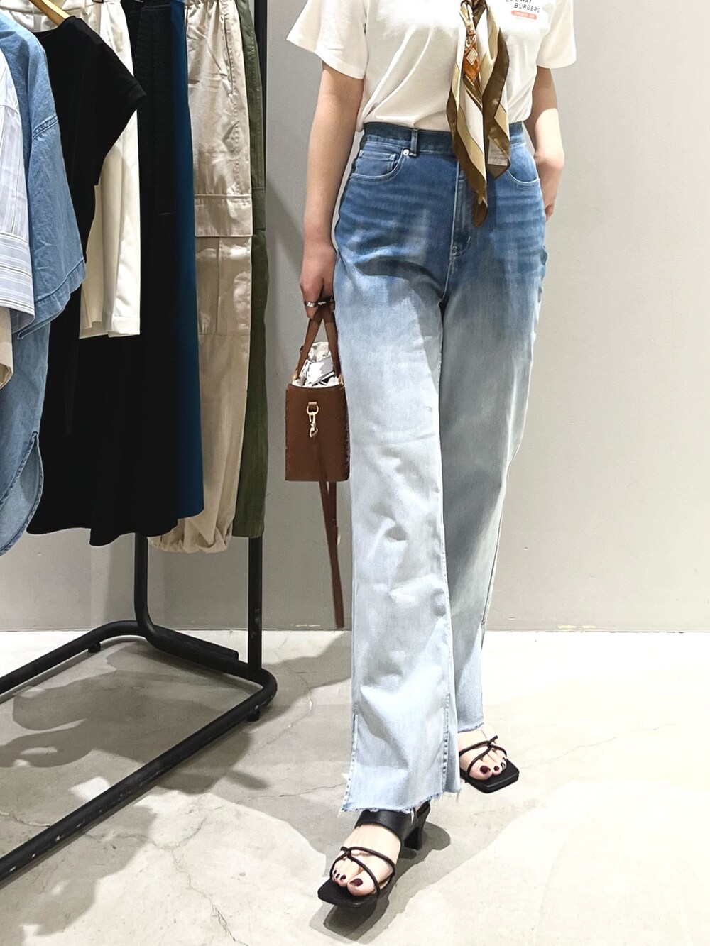 ブルー系のデニムパンツ、ブラック系のサンダル、ブラウン系のショルダーバッグを着用したレディースの夏コーディネートの6枚目の写真