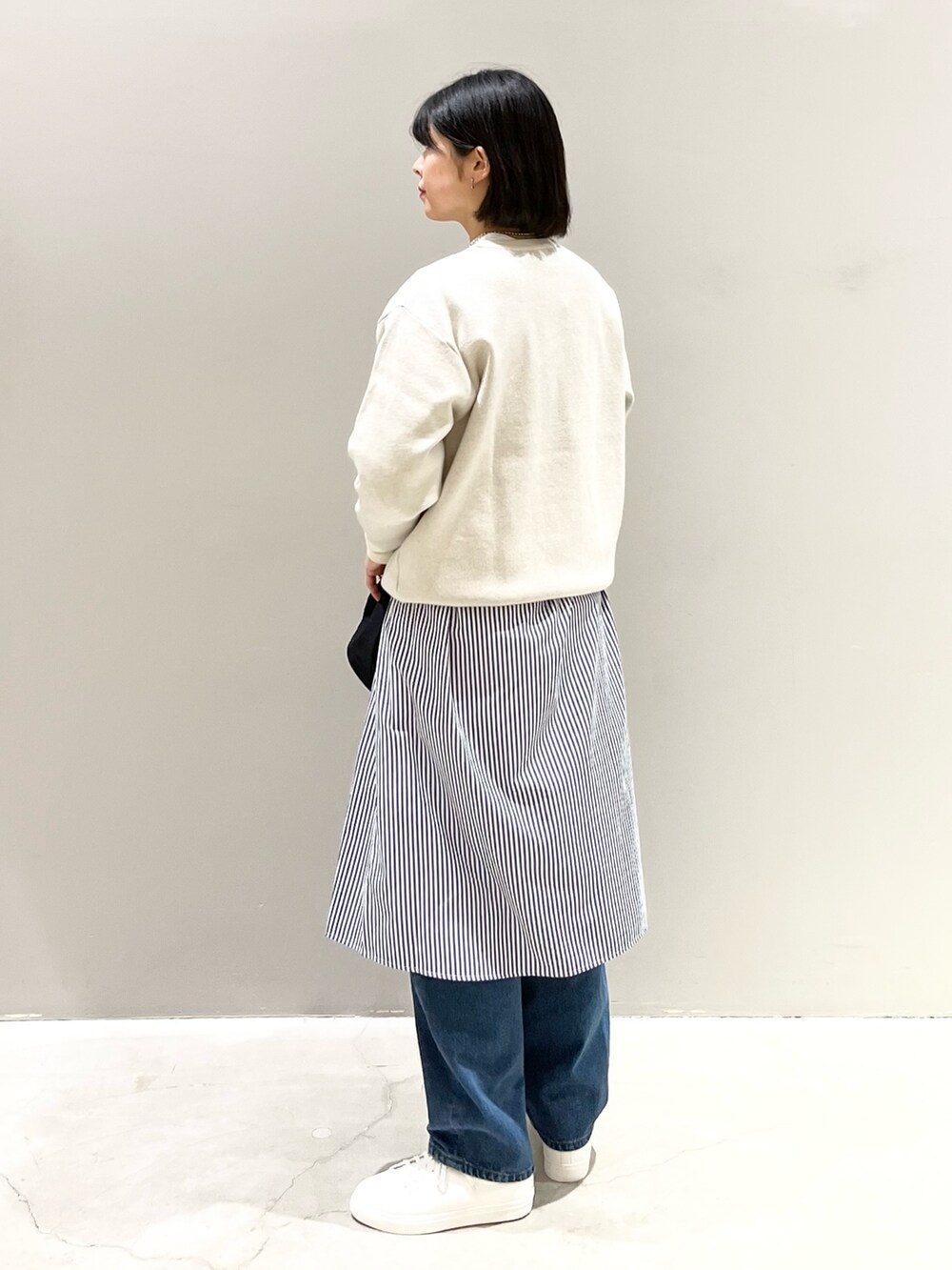 ホワイト系のニット/セーター、ブルー系のデニムパンツ、ホワイト系のスニーカーを着用したレディースの冬コーディネートの3枚目の写真