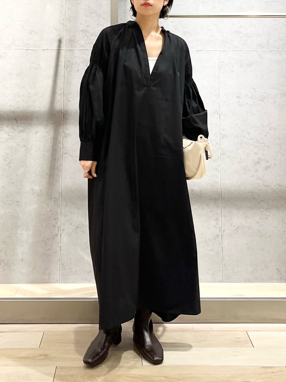 ブラック系のワンピース/ドレス、ブラウン系のブーツ、ホワイト系のショルダーバッグを着用したレディースの秋コーディネートの5枚目の写真