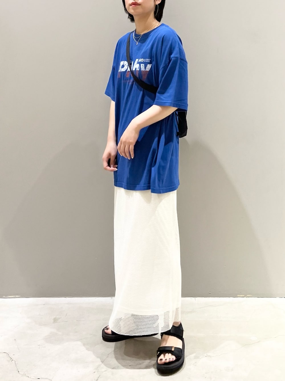 ホワイト系のスカート、ブラック系のサンダル、ブラック系のショルダーバッグを着用したレディースの夏コーディネートの2枚目の写真