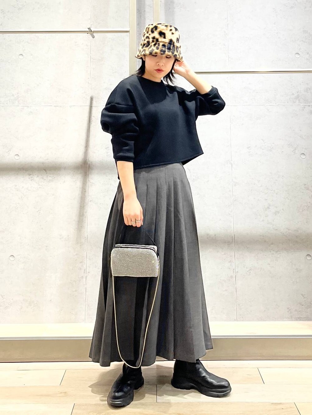 ブラック系のブーツ、ブラック系のTシャツ/カットソー、グレー系のスカートを着用したレディースの冬コーディネートの6枚目の写真