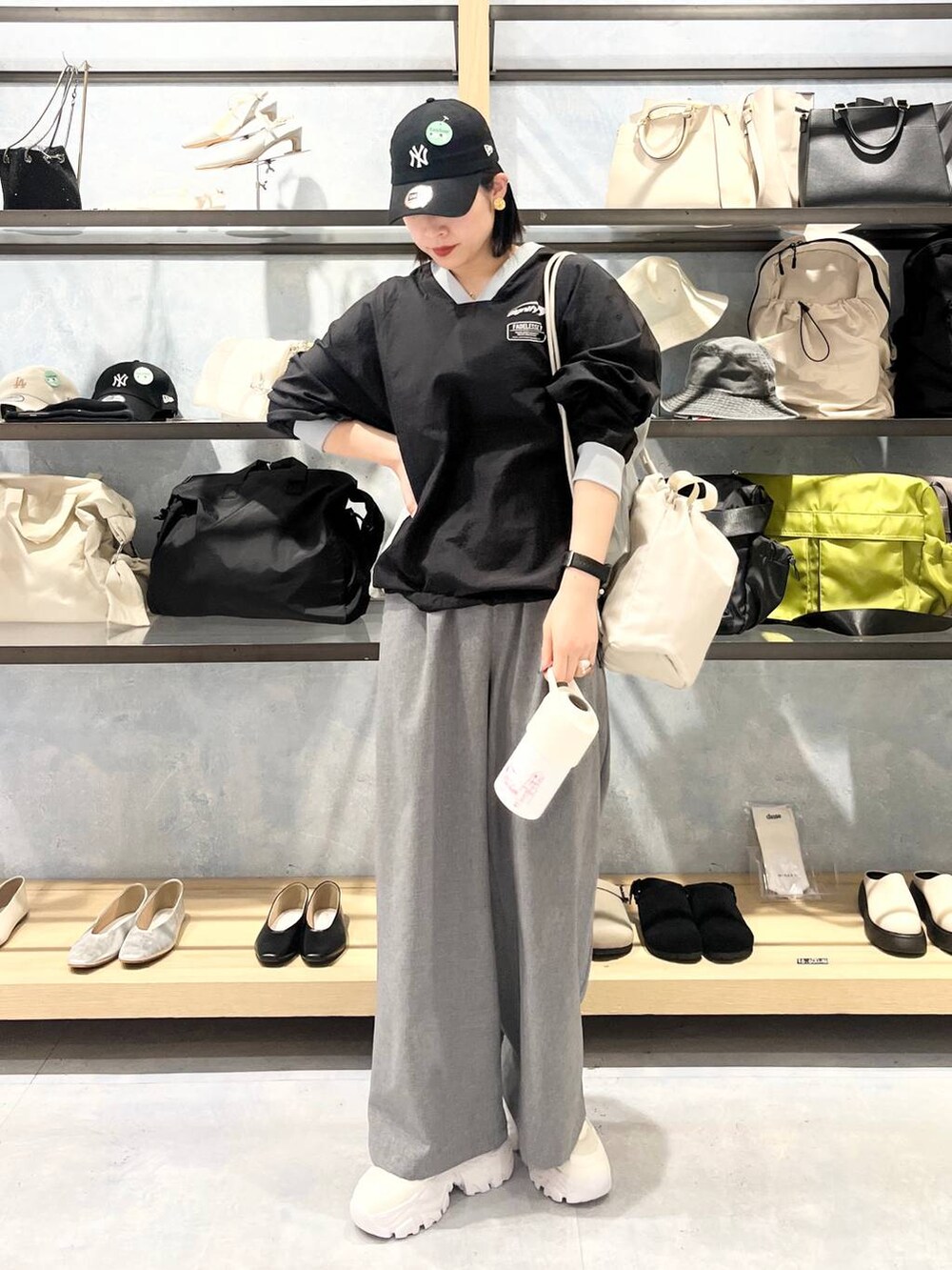 ホワイト系のスニーカー、ベージュ系のショルダーバッグ、グレー系のスラックスを着用したレディースの春コーディネートの3枚目の写真