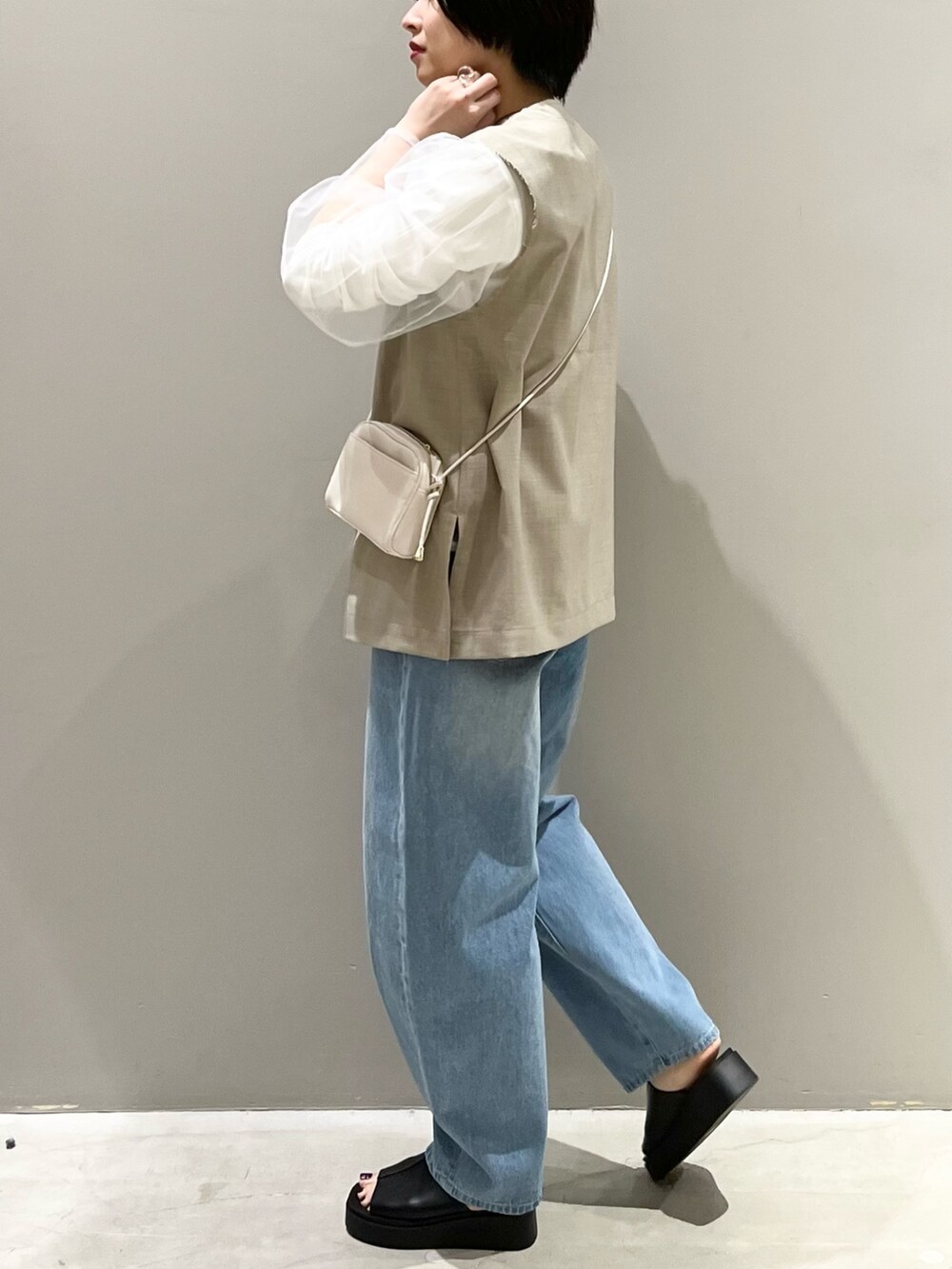 ブルー系のデニムパンツ、ホワイト系のサンダル、ブラック系のバッグを着用したレディースの春コーディネートの2枚目の写真