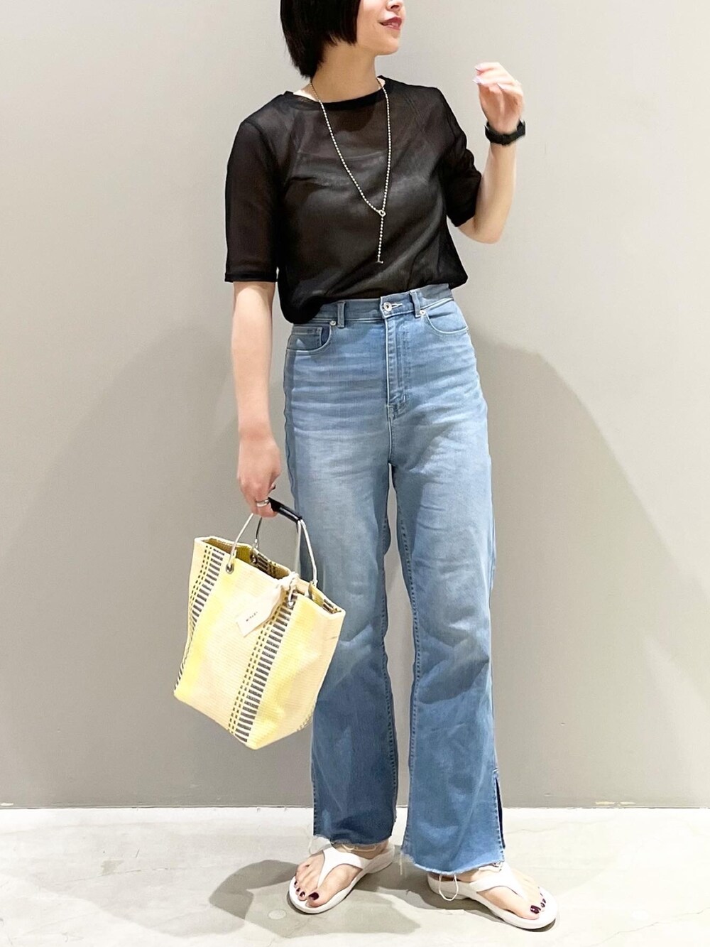 イエロー系のトートバッグ、ブルー系のデニムパンツ、ホワイト系のサンダルを着用したレディースの夏コーディネートの4枚目の写真