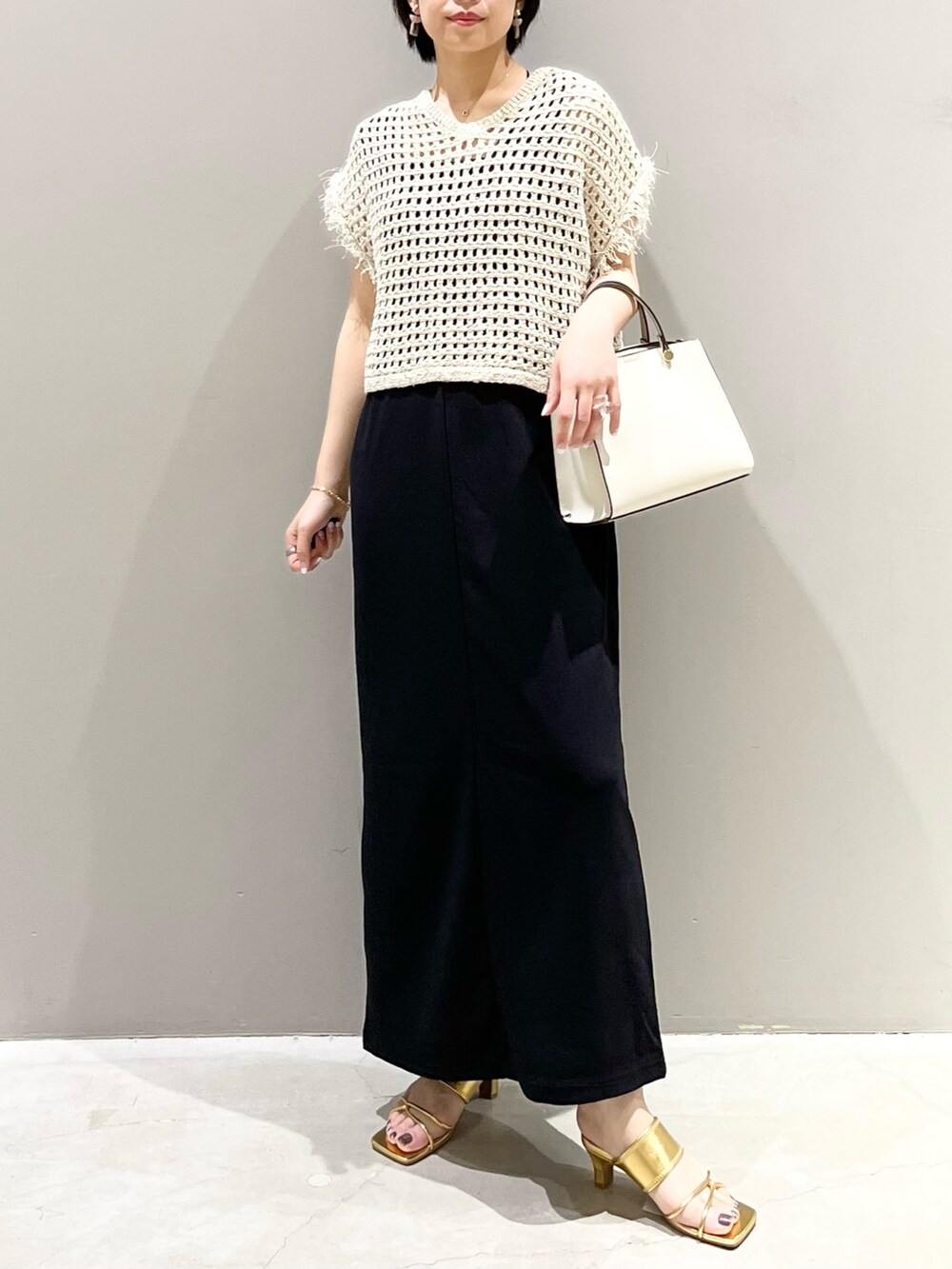 ホワイト系のショルダーバッグ、ブラック系のジャンパースカート、ゴールド系のサンダルを着用したレディースの夏コーディネートの6枚目の写真