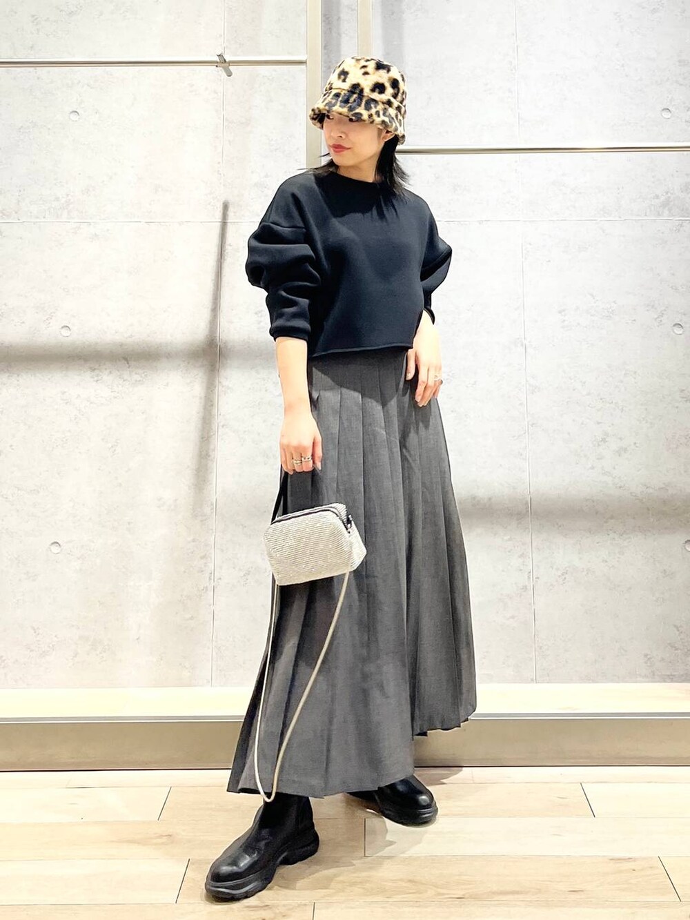 ブラック系のブーツ、ブラック系のTシャツ/カットソー、グレー系のスカートを着用したレディースの冬コーディネートの3枚目の写真