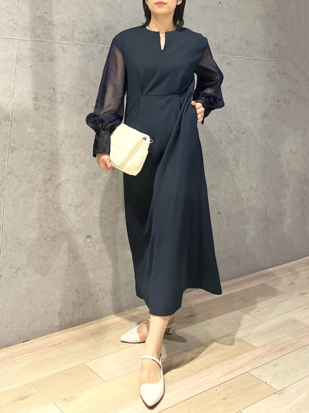 ホワイト系のショルダーバッグ、ホワイト系のパンプス、ブルー系のドレスを着用したレディースの夏コーディネートの2枚目の写真