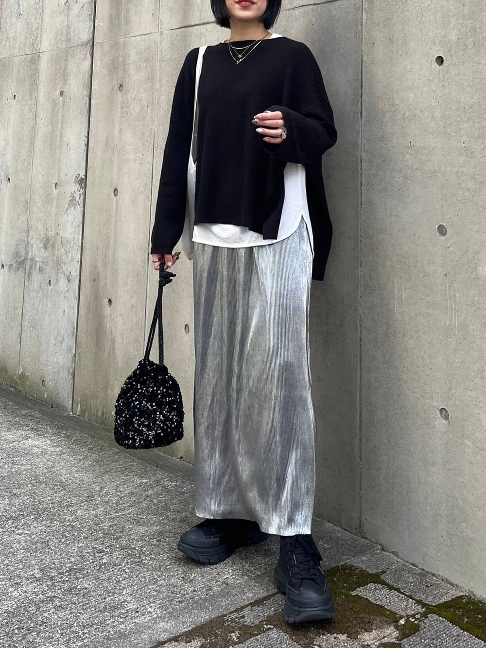 ブラック系のニット/セーター、ホワイト系のTシャツ/カットソー、シルバー系のスカートを着用したレディースの秋コーディネートの7枚目の写真