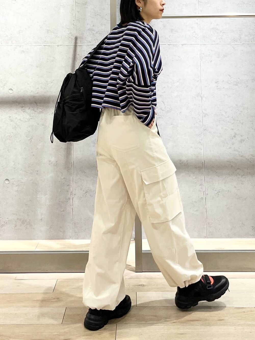 ブラック系のショルダーバッグ、ブルー系のTシャツ/カットソー、ホワイト系のカーゴパンツを着用したレディースの春コーディネートの3枚目の写真