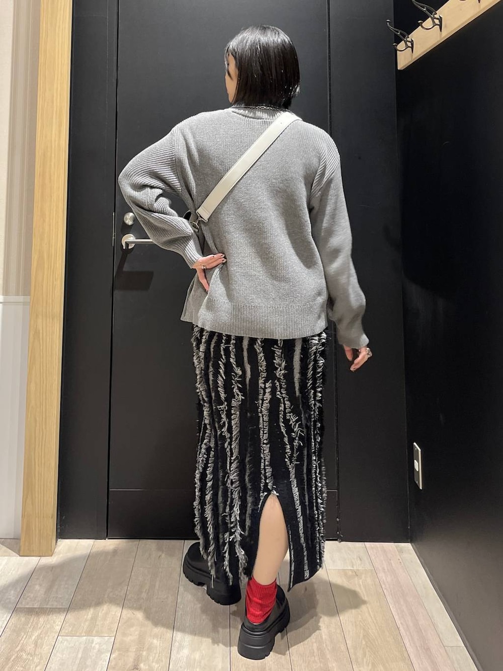 グレー系のショルダーバッグ、ブラック系のスカート、ブラック系のその他シューズを着用したレディースの冬コーディネートの3枚目の写真