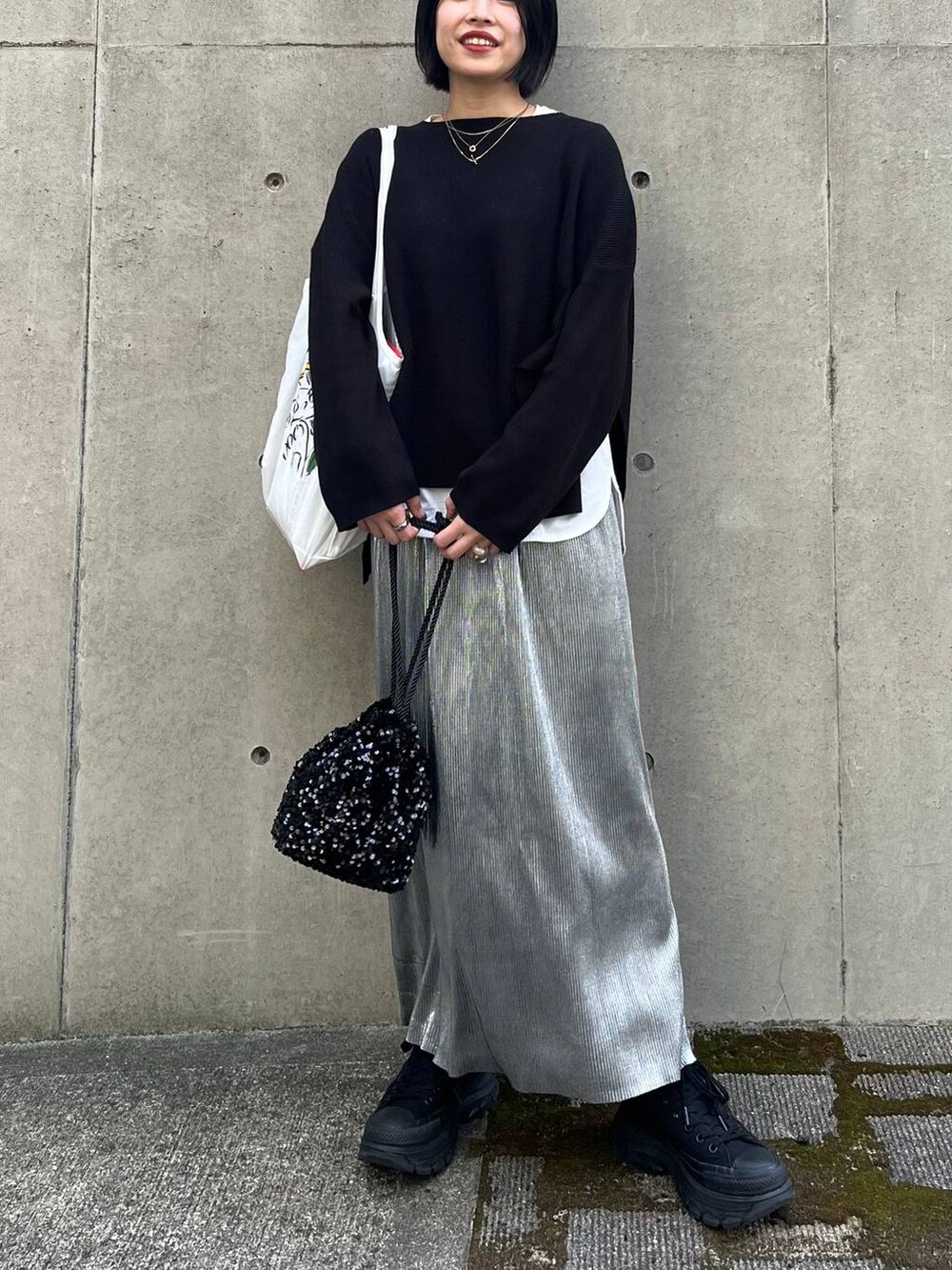 ブラック系のニット/セーター、ホワイト系のTシャツ/カットソー、シルバー系のスカートを着用したレディースの秋コーディネートの9枚目の写真