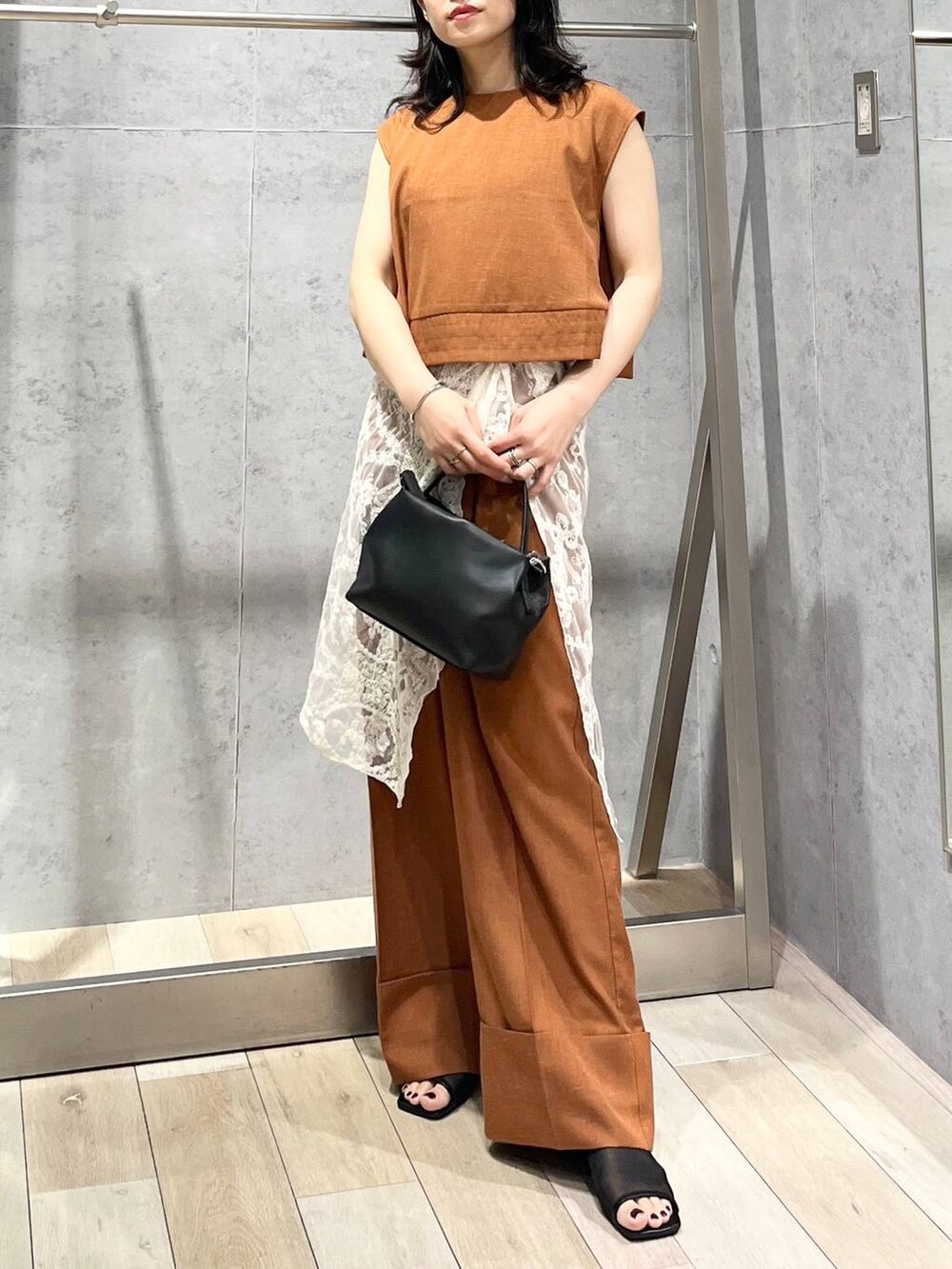 ブラック系のサンダル、オレンジ系のシャツ/ブラウス、ブラック系のショルダーバッグを着用したレディースの夏コーディネートの2枚目の写真