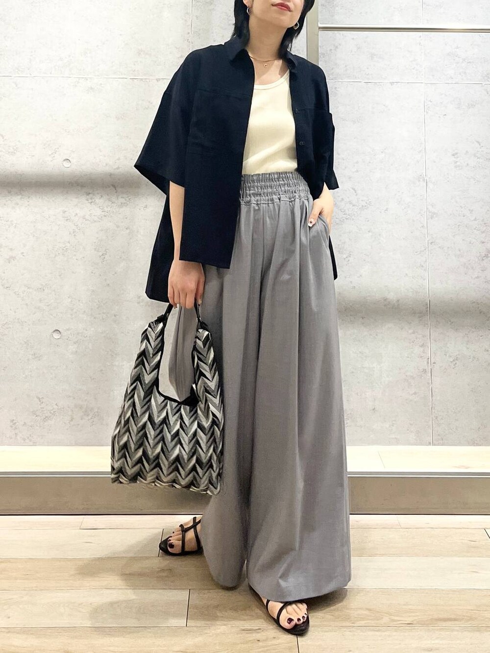 ブラック系のサンダル、ブラック系のハンドバッグ、ホワイト系のタンクトップを着用したレディースの夏コーディネートの7枚目の写真