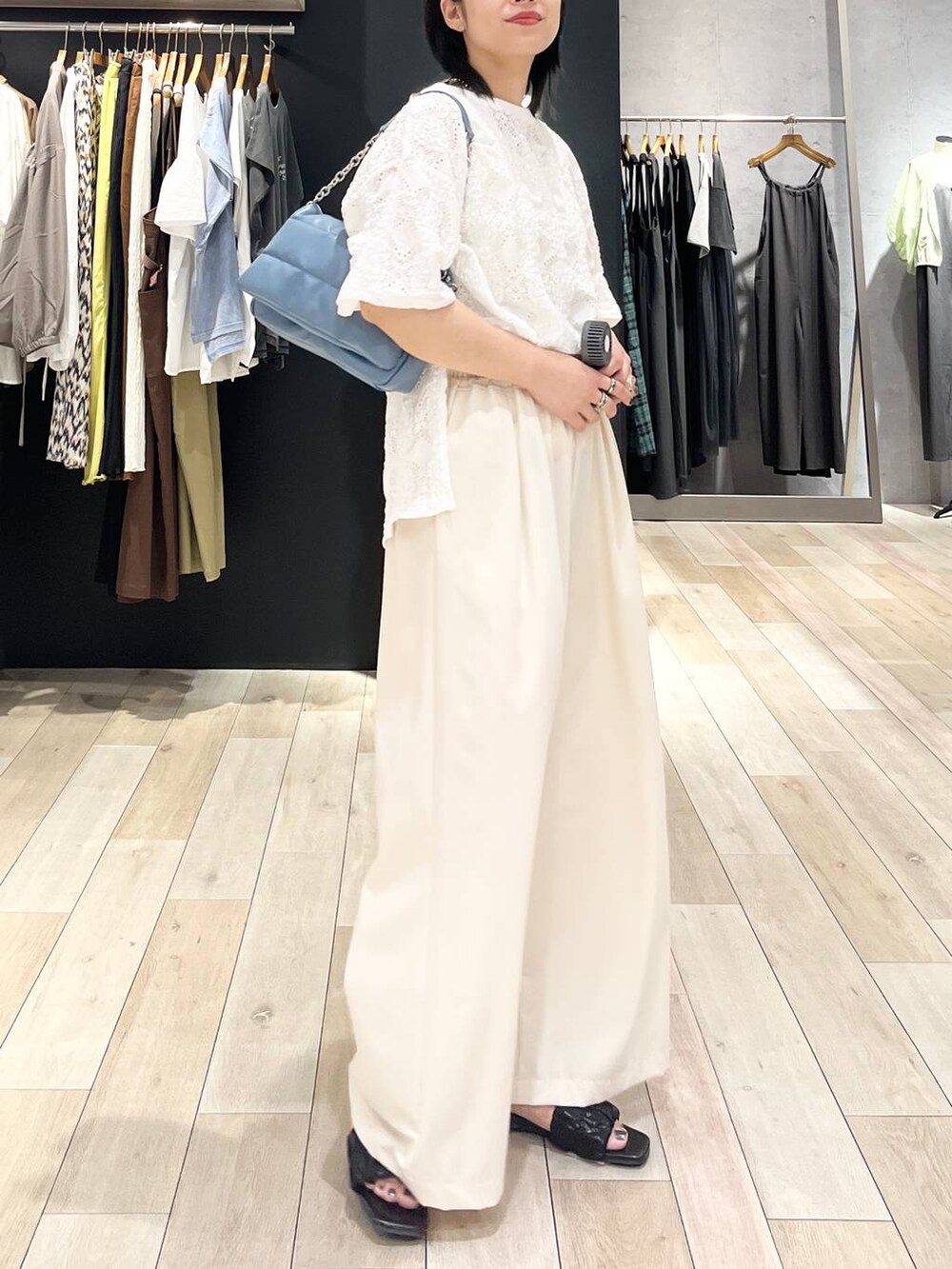 ブルー系のショルダーバッグ、ホワイト系のスラックス、ホワイト系のTシャツ/カットソーを着用したレディースの夏コーディネートの4枚目の写真