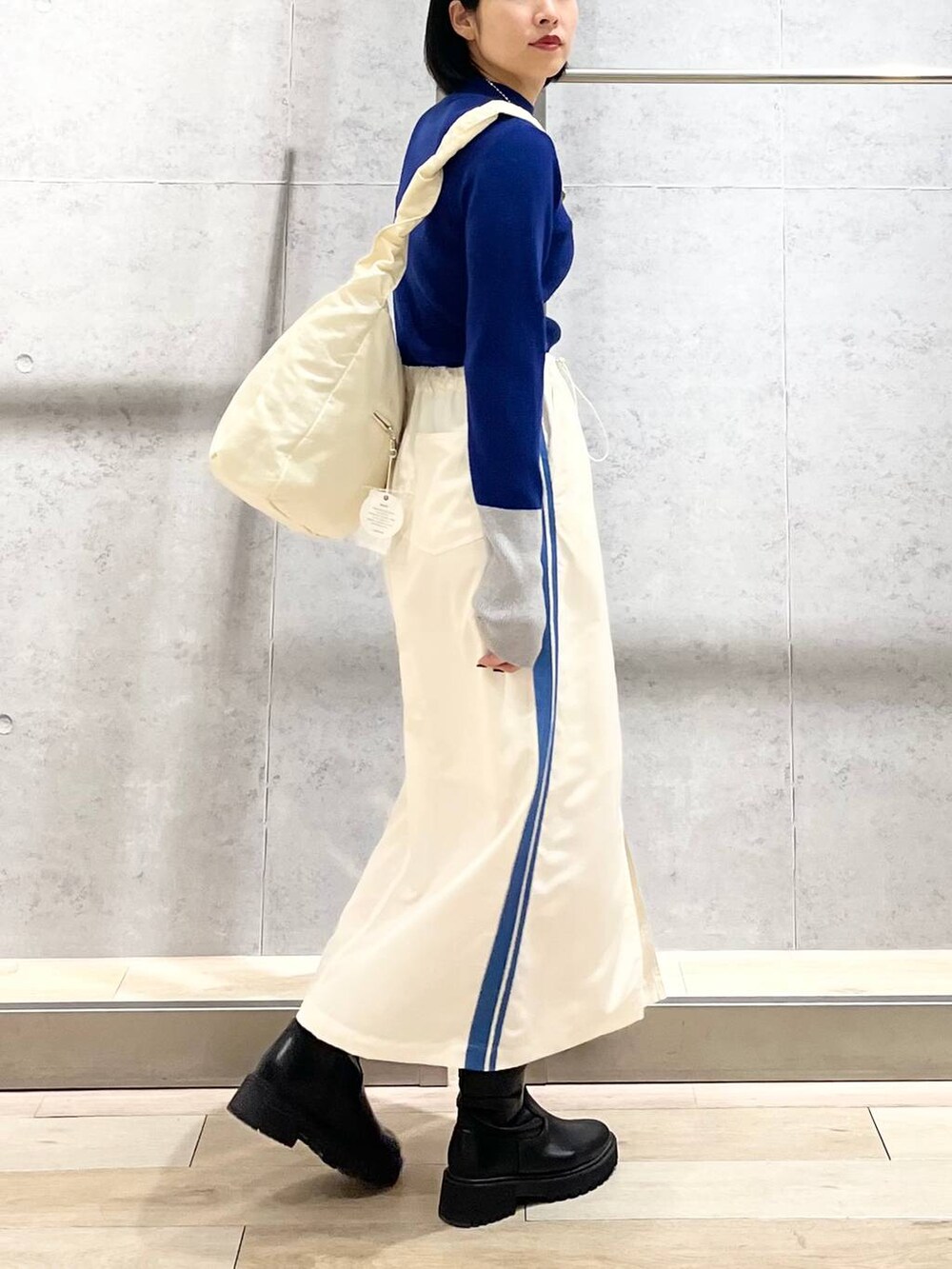 ブラック系のブーツ、ホワイト系のショルダーバッグ、ホワイト系のスカートを着用したレディースの冬コーディネートの8枚目の写真