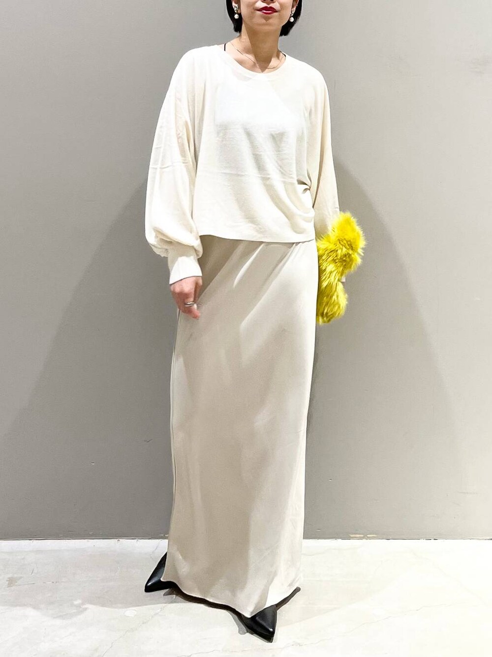 ブラック系のキャミソール、ホワイト系のニット/セーター、イエロー系のハンドバッグを着用したレディースの秋コーディネートの9枚目の写真