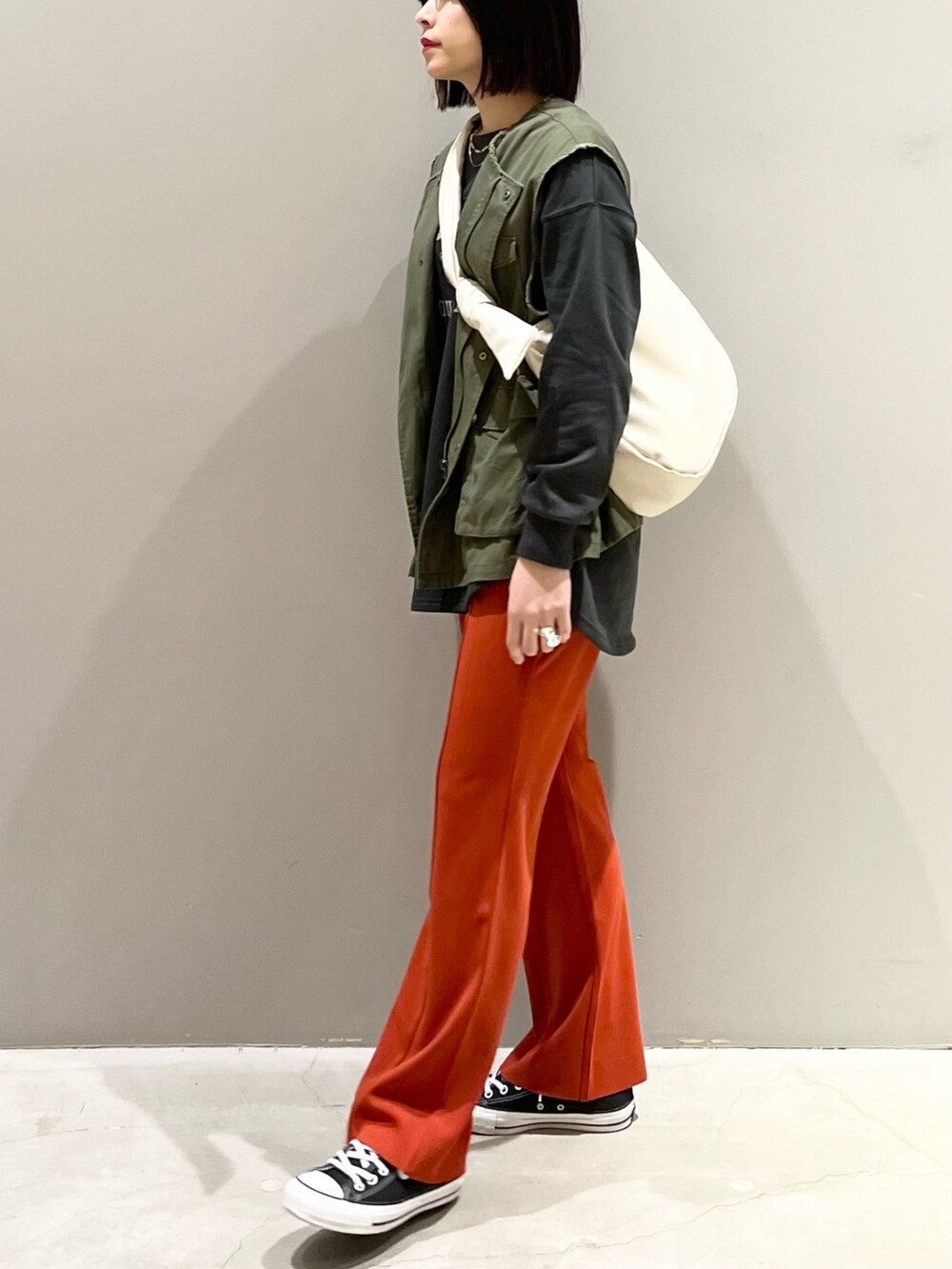 ブラック系のスニーカー、オレンジ系のその他パンツ、グリーン系のジャケット/アウターを着用したレディースの春コーディネートの3枚目の写真