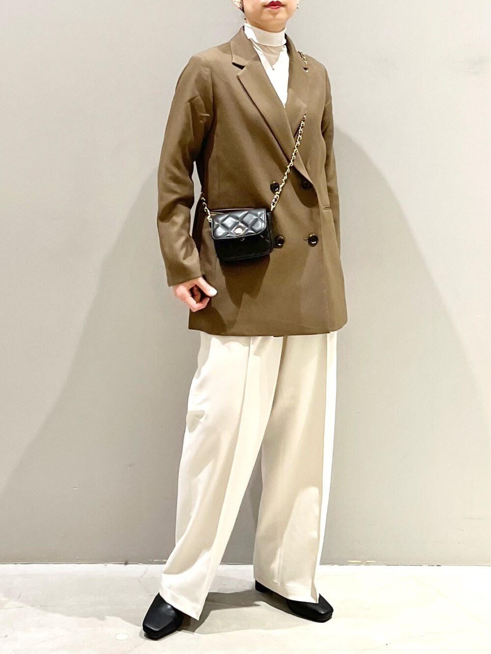 ホワイト系のスラックス、ブラック系のブーツ、ブラック系のバッグを着用したレディースの秋コーディネートの5枚目の写真