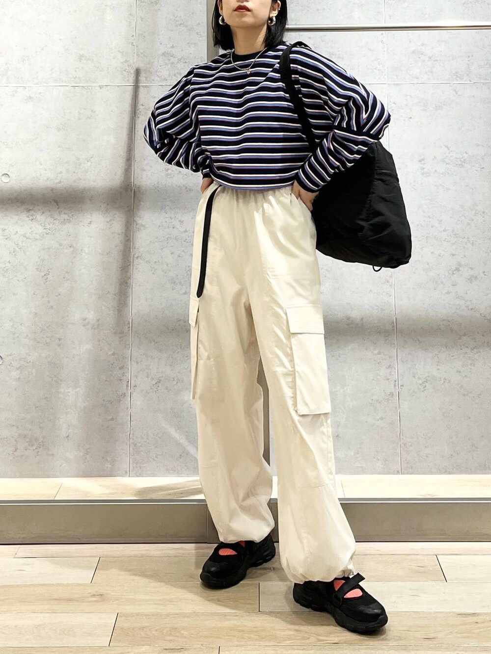 ブラック系のショルダーバッグ、ブルー系のTシャツ/カットソー、ホワイト系のカーゴパンツを着用したレディースの春コーディネートの9枚目の写真
