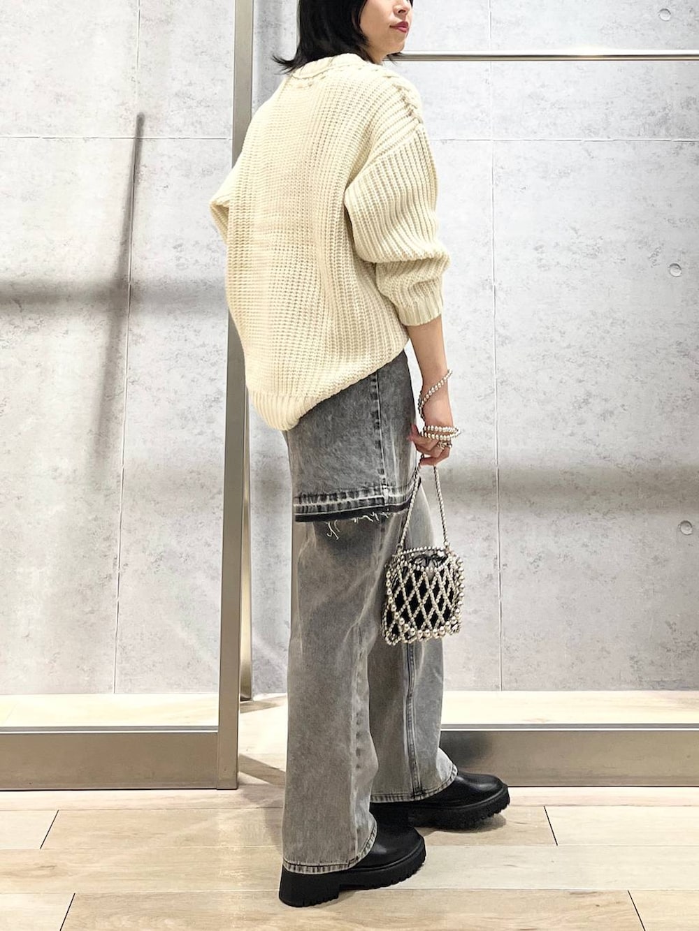 シルバー系のショルダーバッグ、ブラック系のデニムパンツ、ブラック系のブーツを着用したレディースの秋コーディネートの4枚目の写真