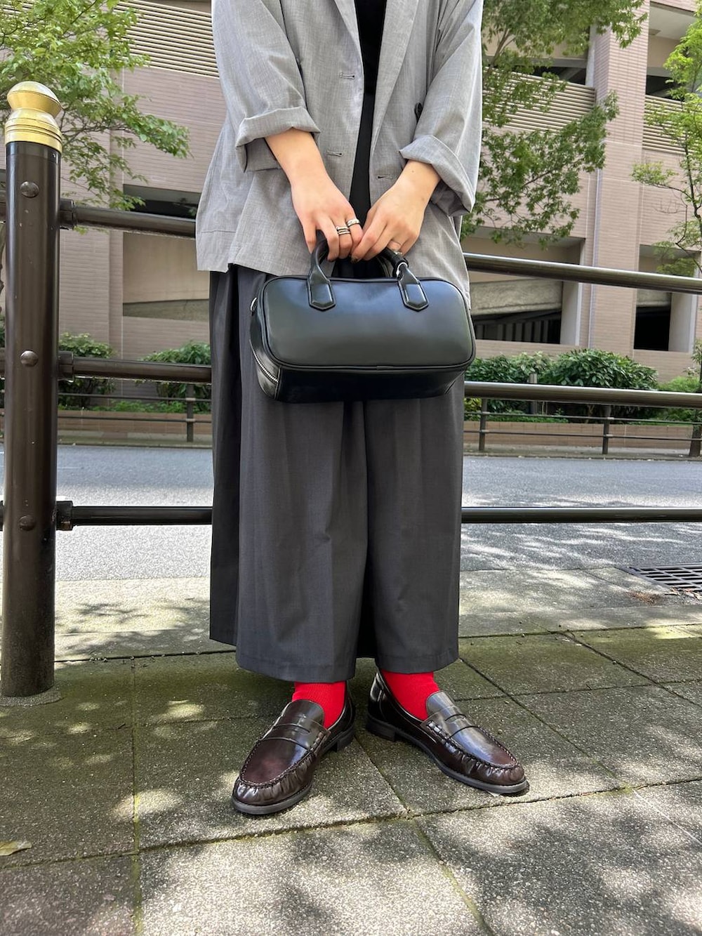 ブラック系のボストンバッグ、グレー系のテーラードジャケット、グレー系のスカートを着用したレディースの夏コーディネートの3枚目の写真