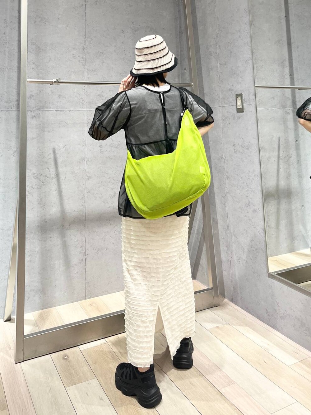 ブラック系のスニーカー、ホワイト系のスカート、グリーン系のショルダーバッグを着用したレディースの春コーディネートの4枚目の写真