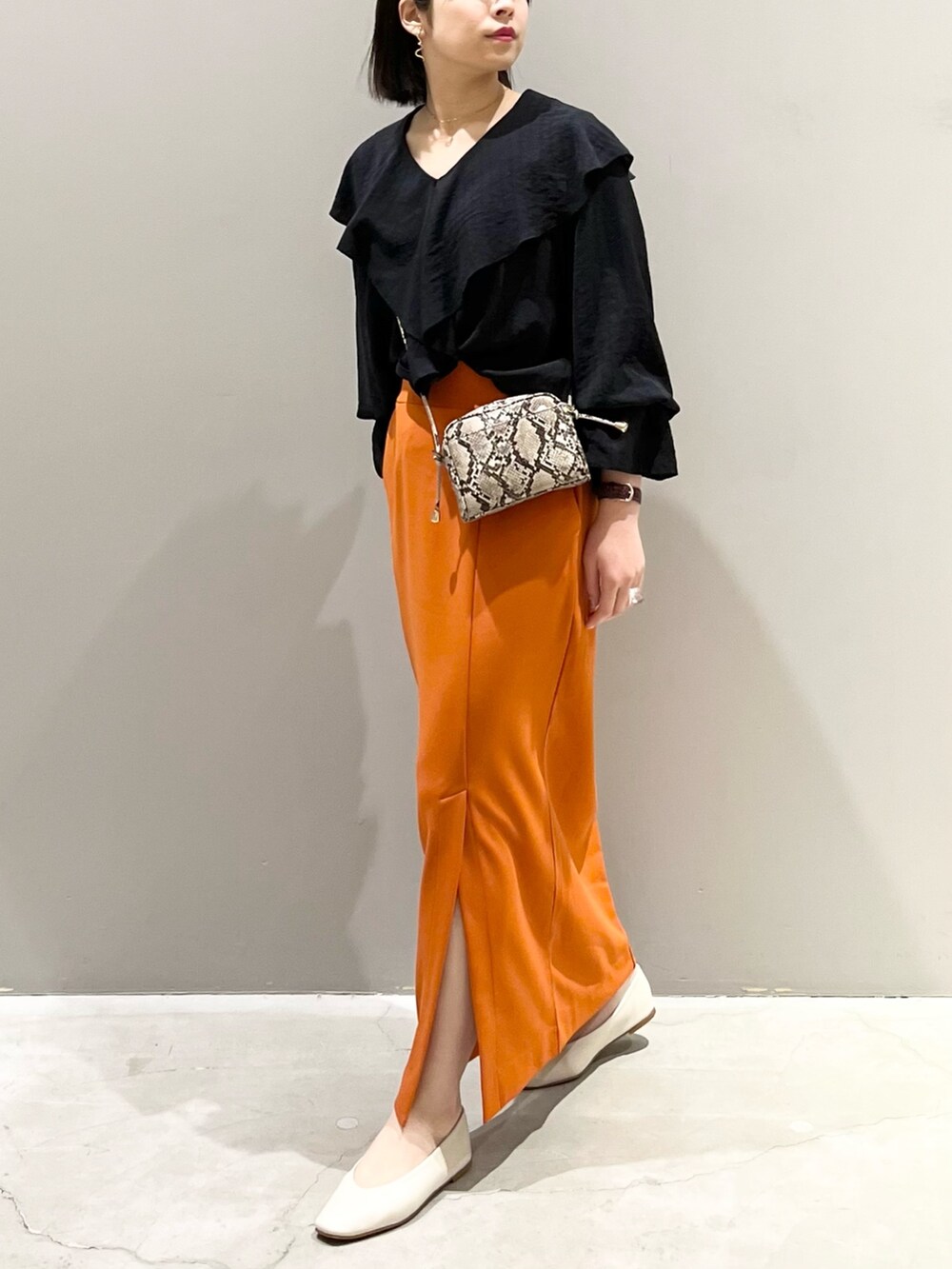 オレンジ系のスカート、ホワイト系のパンプス、その他のショルダーバッグを着用したレディースの春コーディネートの7枚目の写真