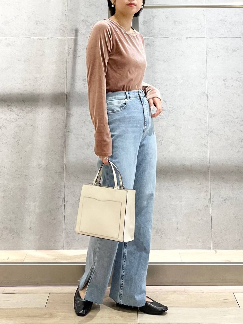 ブラック系のパンプス、ブルー系のデニムパンツ、ホワイト系のショルダーバッグを着用したレディースの秋コーディネートの3枚目の写真