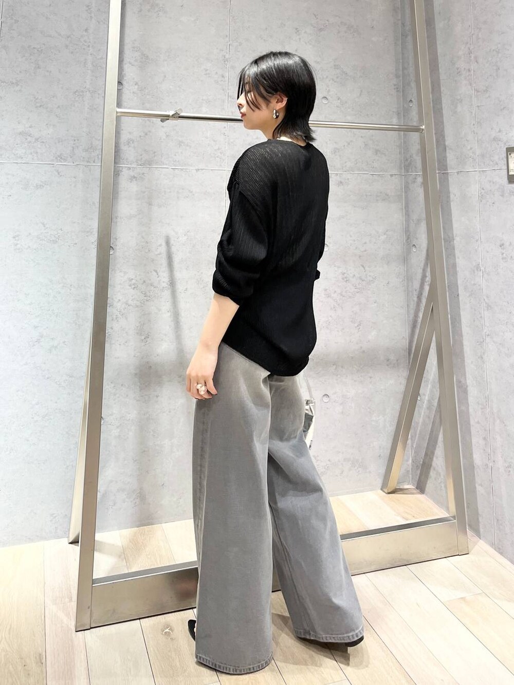 シルバー系のハンドバッグ、ブラック系のサンダル、グレー系のデニムパンツを着用したレディースの春コーディネートの4枚目の写真