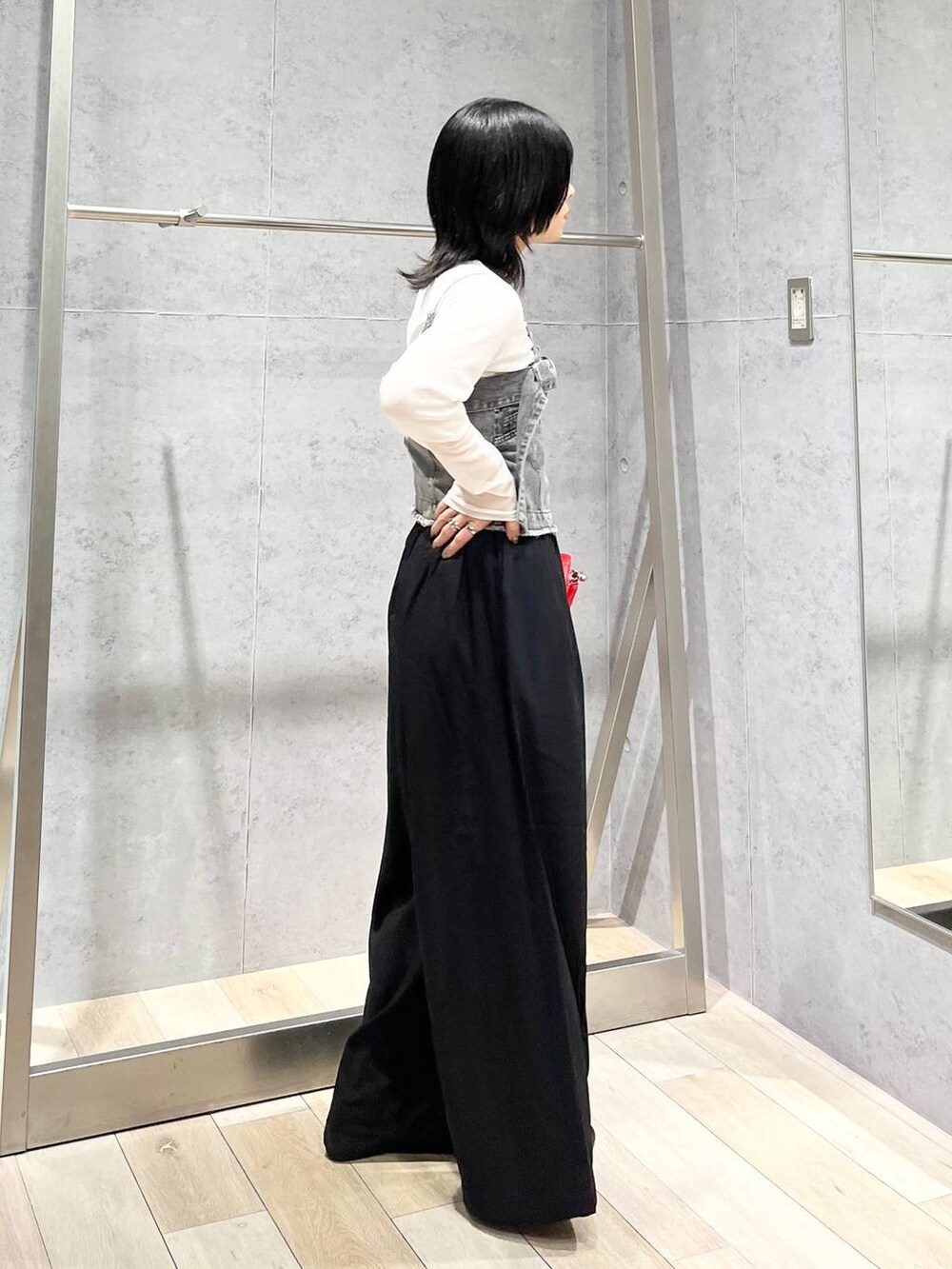 レッド系のショルダーバッグ、ブラック系のスラックス、ブラック系のバレエシューズを着用したレディースの夏コーディネートの3枚目の写真