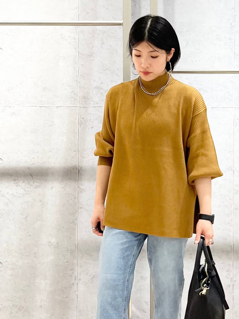 ブラウン系のニット/セーター、ブルー系のデニムパンツ、ベージュ系のショルダーバッグを着用したレディースの秋コーディネートの8枚目の写真