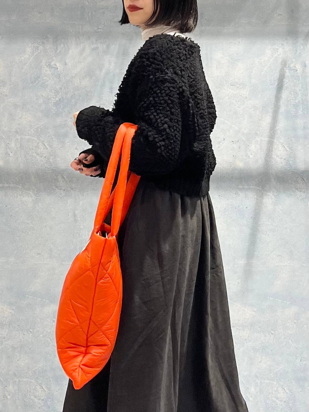 オレンジ系のトートバッグ、グレー系のワンピース、ブラック系のブーツを着用したレディースの冬コーディネートの3枚目の写真