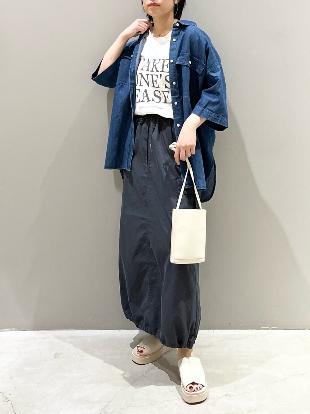 オレンジ系のバッグ、グレー系のスカート、ベージュ系のサンダルを着用したレディースの夏コーディネートの2枚目の写真