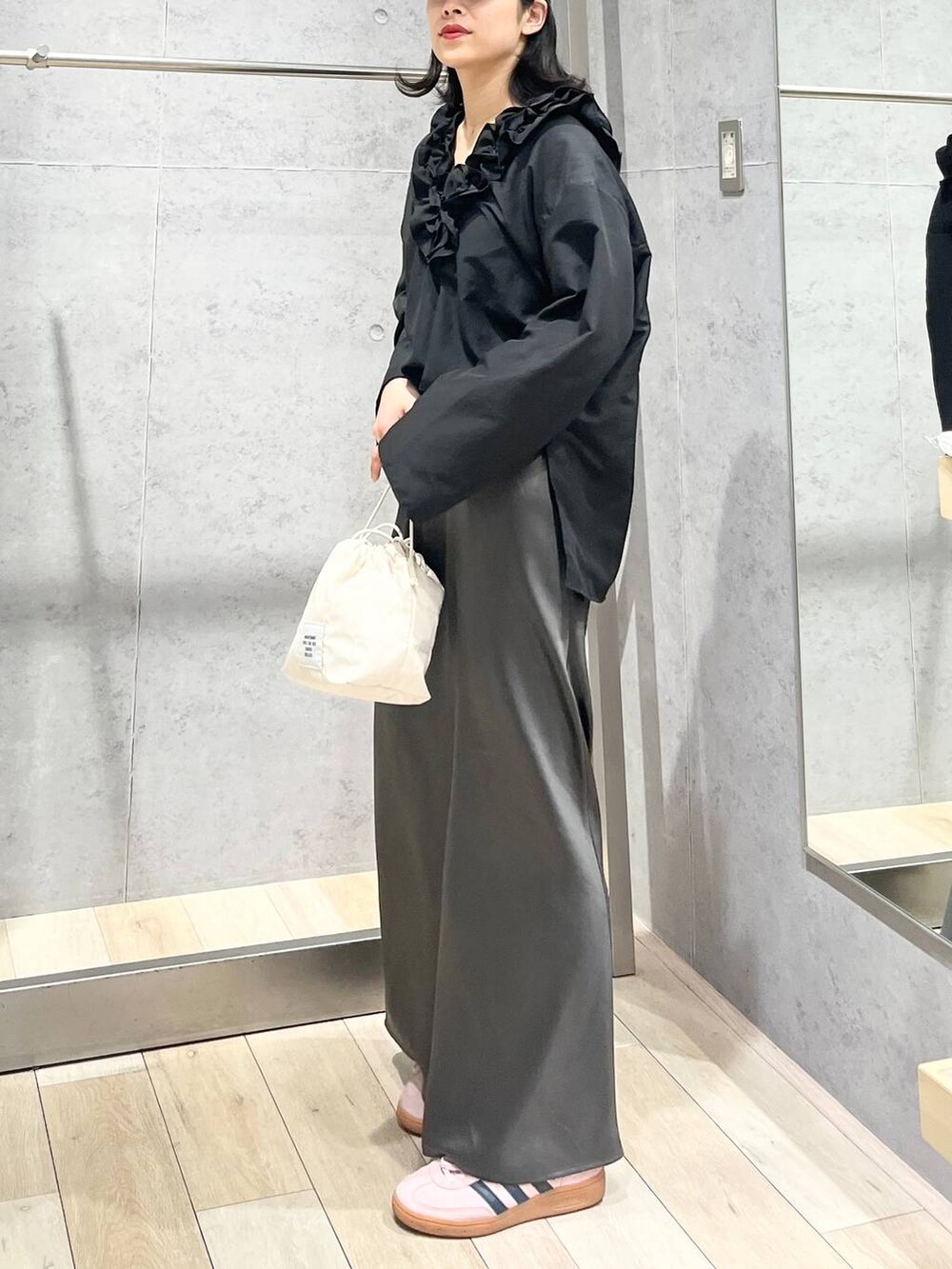 グレー系のスカート、ホワイト系のショルダーバッグ、ブラック系のキャップを着用したレディースの春コーディネートの4枚目の写真