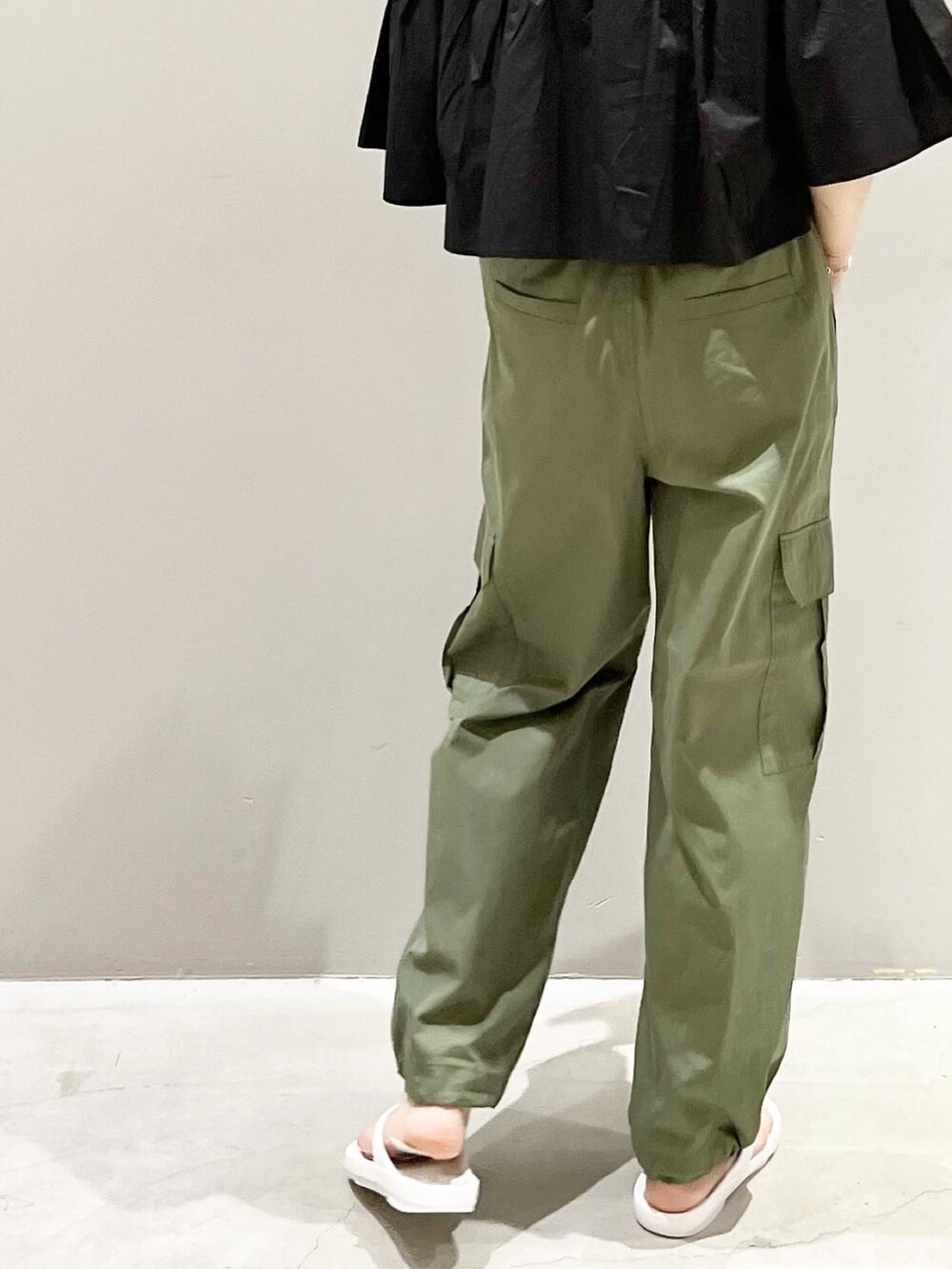 グリーン系のパンツ、ブラック系のTシャツ/カットソー、ホワイト系のショルダーバッグを着用したレディースの春コーディネートの6枚目の写真