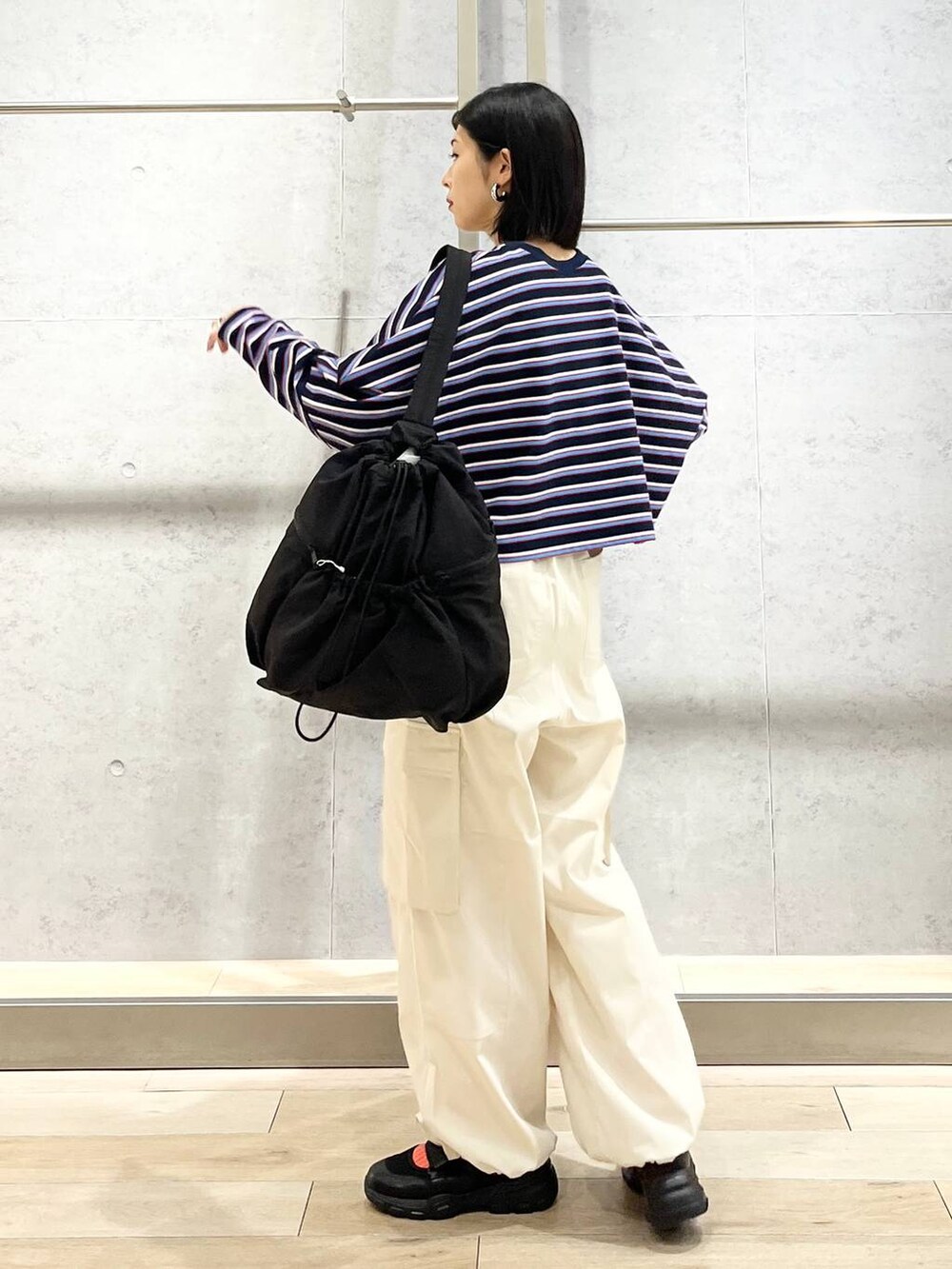 ブラック系のショルダーバッグ、ブルー系のTシャツ/カットソー、ホワイト系のカーゴパンツを着用したレディースの春コーディネートの7枚目の写真