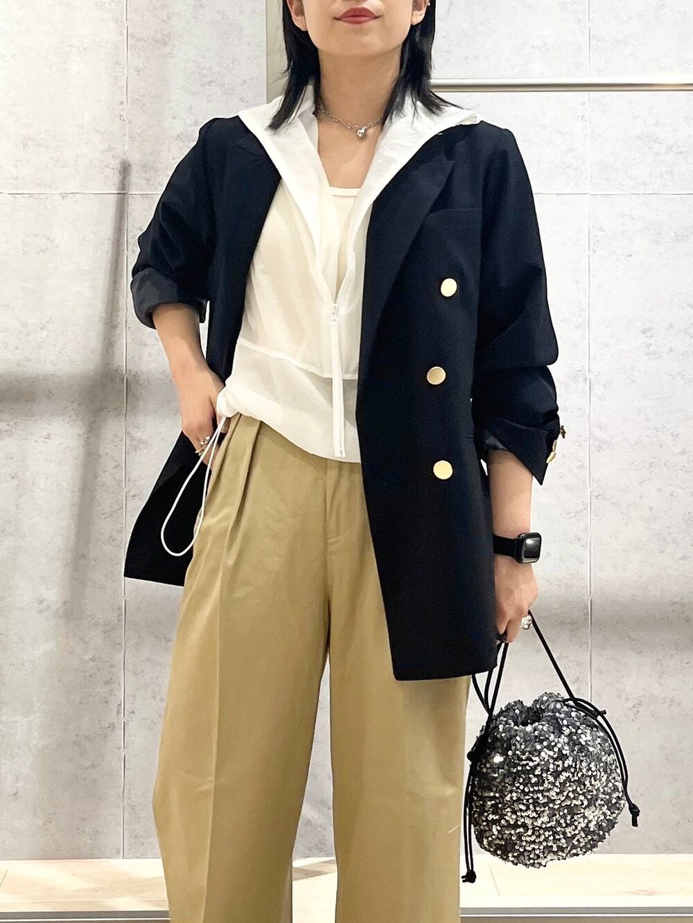 ブルー系のテーラードジャケット、ベージュ系のチノパンツ、ホワイト系のタンクトップを着用したレディースの夏コーディネートの2枚目の写真