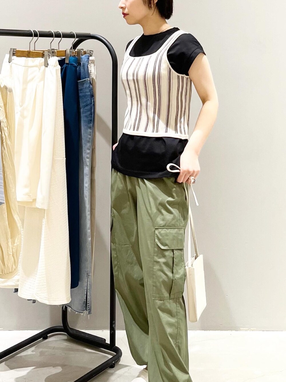 ベージュ系のタンクトップ、ブラック系のTシャツ/カットソー、グリーン系のパンツを着用したレディースの夏コーディネートの3枚目の写真