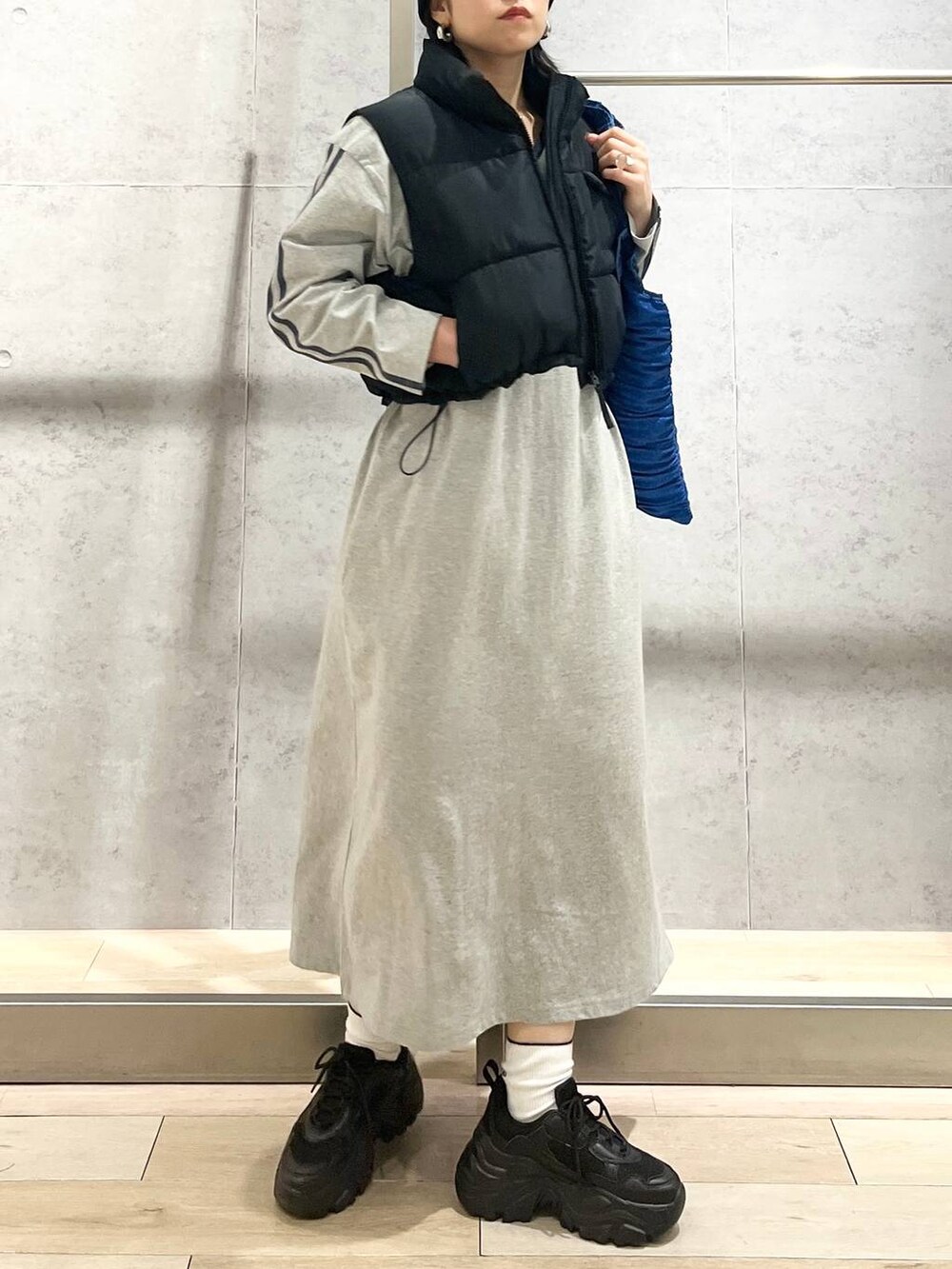 ブラック系のスニーカー、ブルー系のトートバッグ、ブラック系のベストを着用したレディースの冬コーディネートの2枚目の写真