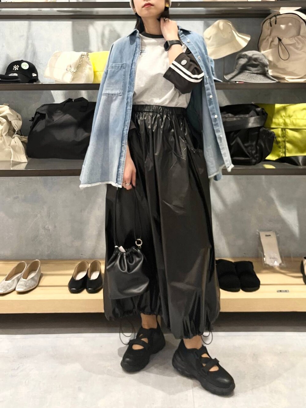 ブラック系のショルダーバッグ、ブラック系のTシャツ/カットソー、ブラック系のスニーカーを着用したレディースの春コーディネートの2枚目の写真