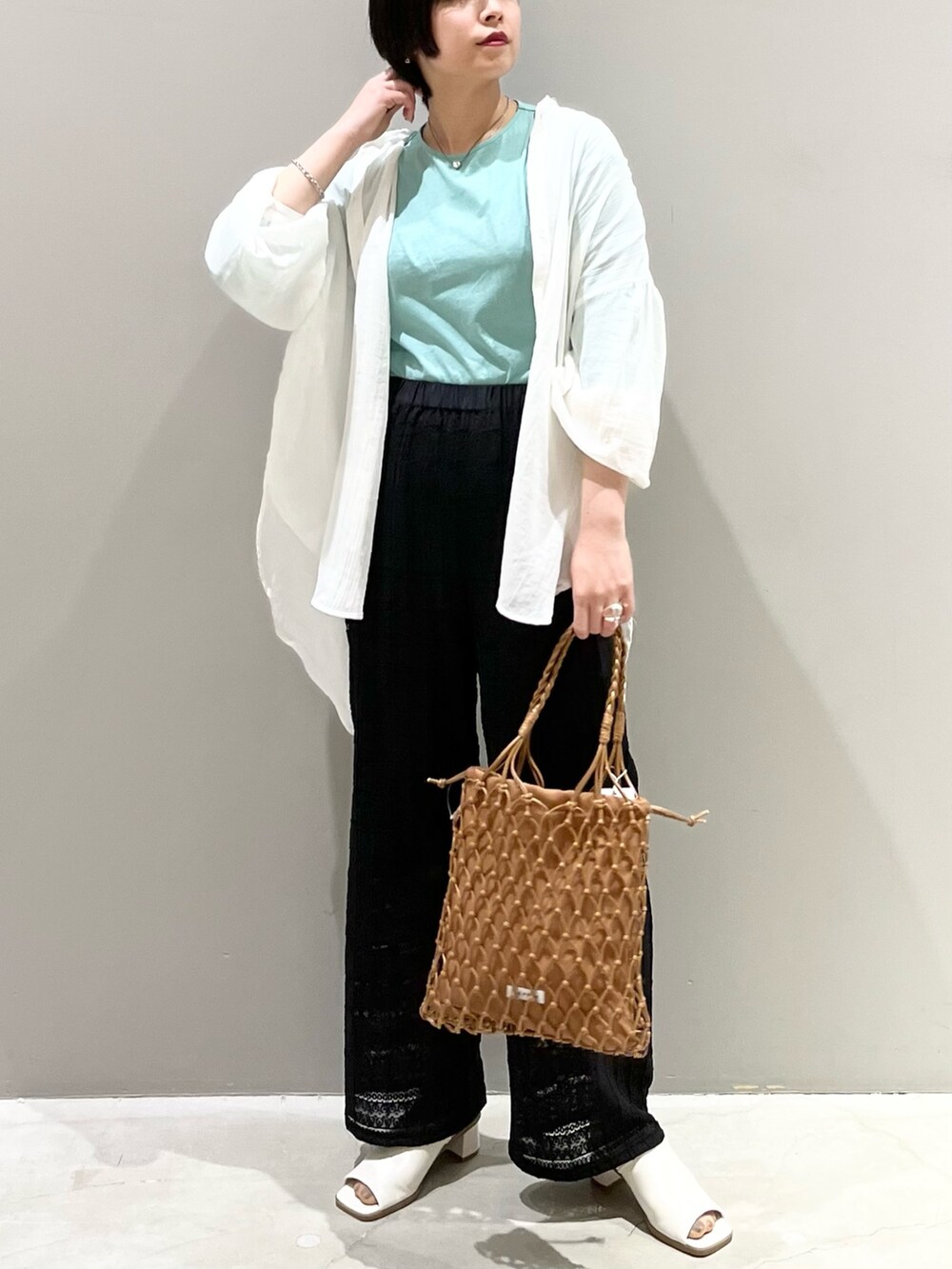 ブラック系のその他パンツ、ホワイト系のサンダル、ベージュ系のバッグを着用したレディースの春コーディネートの3枚目の写真