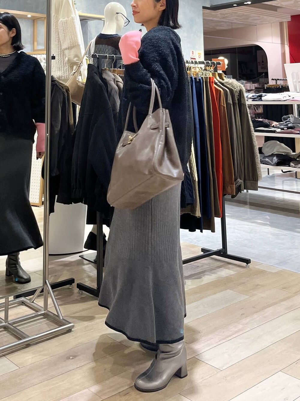 グレー系のニット/セーター、ブラック系のスカート、ブラウン系のトートバッグを着用したレディースの秋コーディネートの2枚目の写真