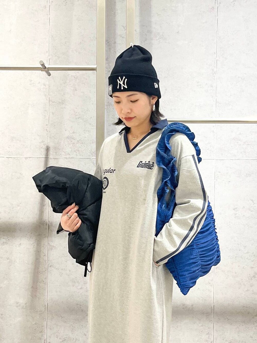 ブラック系のスニーカー、ブルー系のトートバッグ、ブラック系のベストを着用したレディースの冬コーディネートの6枚目の写真