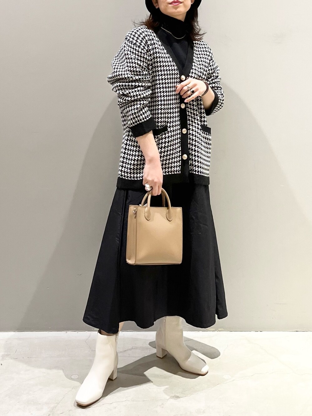 ベージュ系のショルダーバッグ、ホワイト系のブーツ、ブラック系のワンピースを着用したレディースの冬コーディネートの5枚目の写真