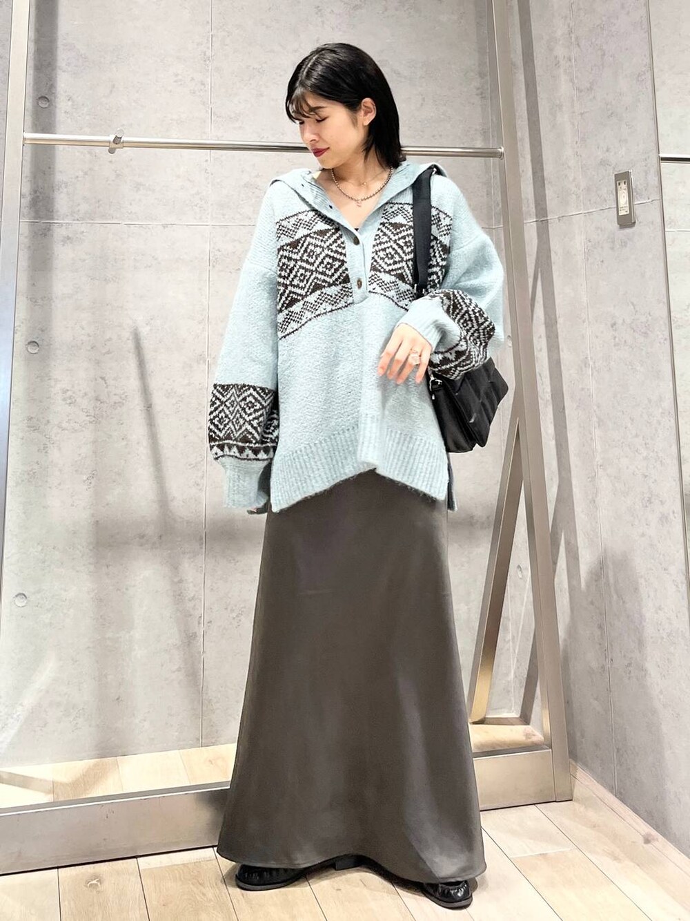 ブラック系のショルダーバッグ、グレー系のスカート、ブラック系のローファーを着用したレディースの秋コーディネートの2枚目の写真
