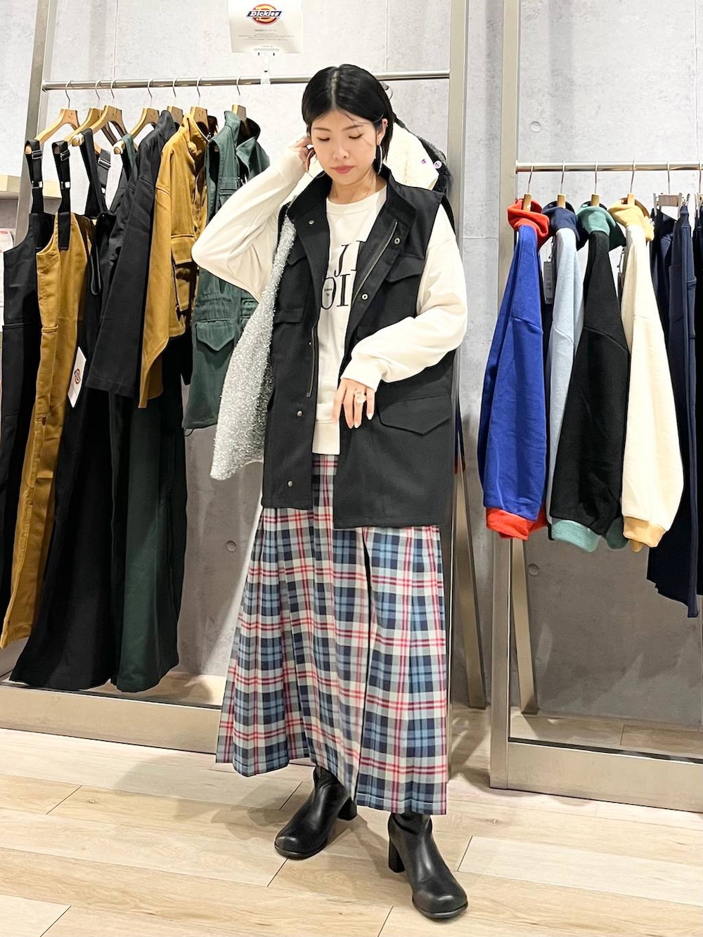 ブラック系のベスト、ホワイト系のスウェット、ブラック系のブーツを着用したレディースの秋コーディネートの2枚目の写真