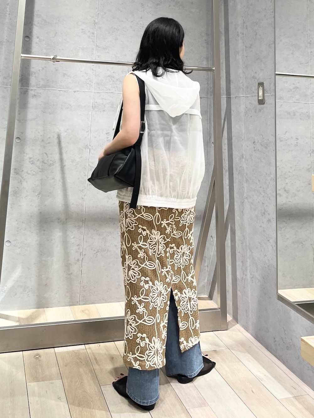 ブラック系のショルダーバッグ、ブルー系のデニムパンツ、ブラック系のサンダルを着用したレディースの春コーディネートの6枚目の写真
