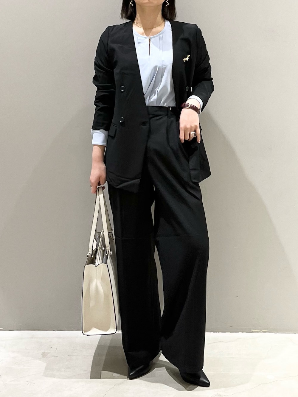ブラック系のパンツ、ホワイト系のトートバッグ、ブラック系のパンプスを着用したレディースの冬コーディネートの2枚目の写真
