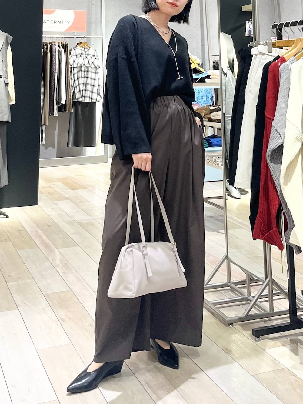ブラック系のニット/セーター、ブラウン系のその他パンツ、ベージュ系のボストンバッグを着用したレディースの秋コーディネートの2枚目の写真
