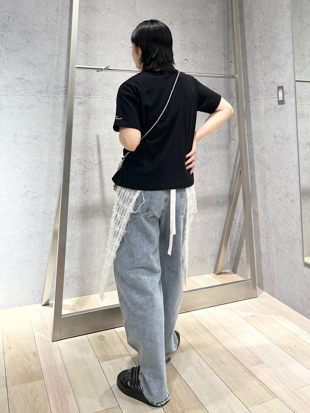 ブラック系のTシャツ/カットソー、ブラック系のサンダル、ブルー系のデニムパンツを着用したレディースの夏コーディネートの5枚目の写真